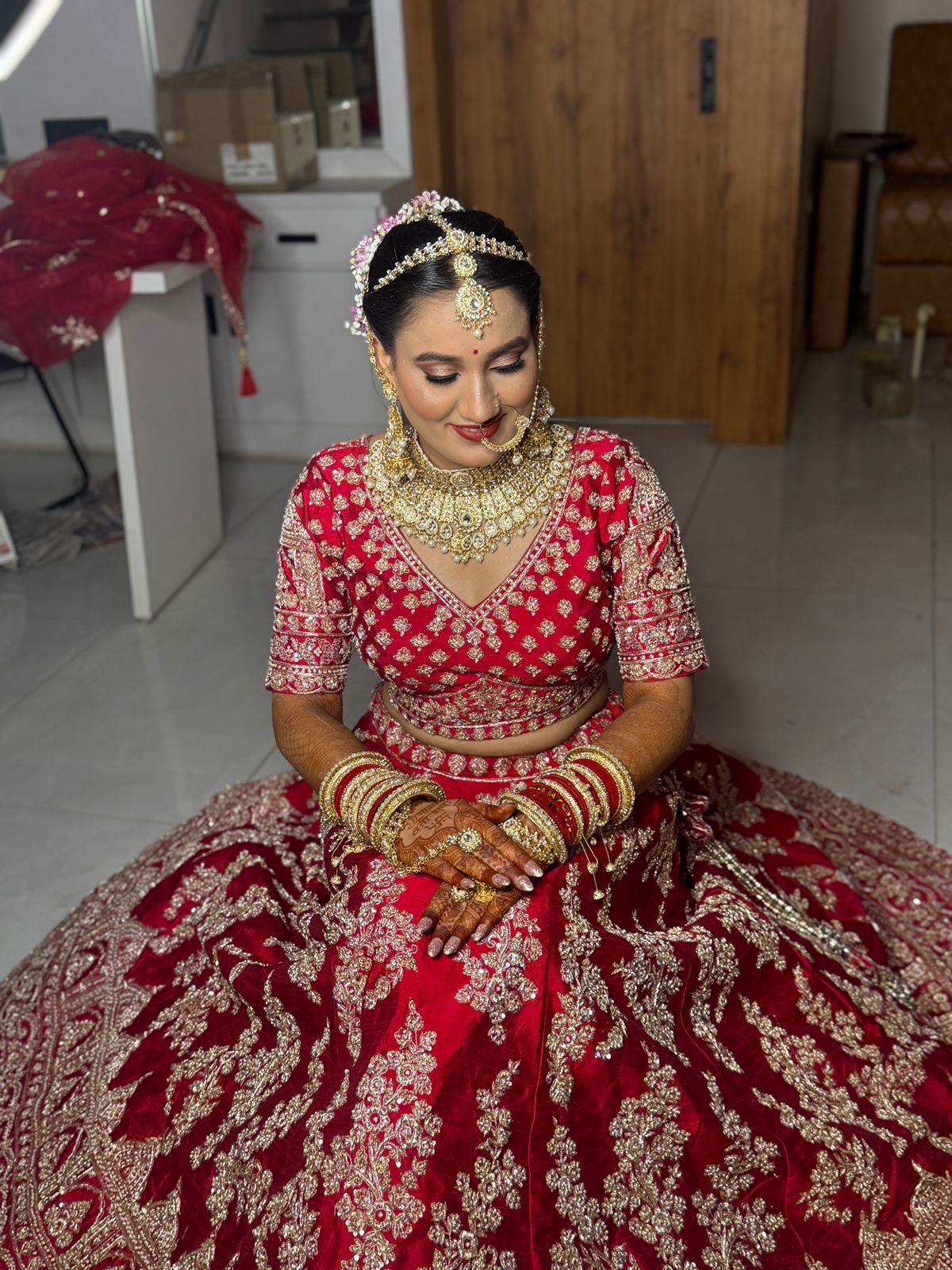 Bride in red lehenga seated with mehndi hands