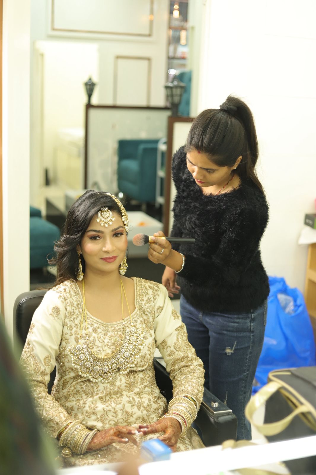 Stylist applying makeup on bride in salon